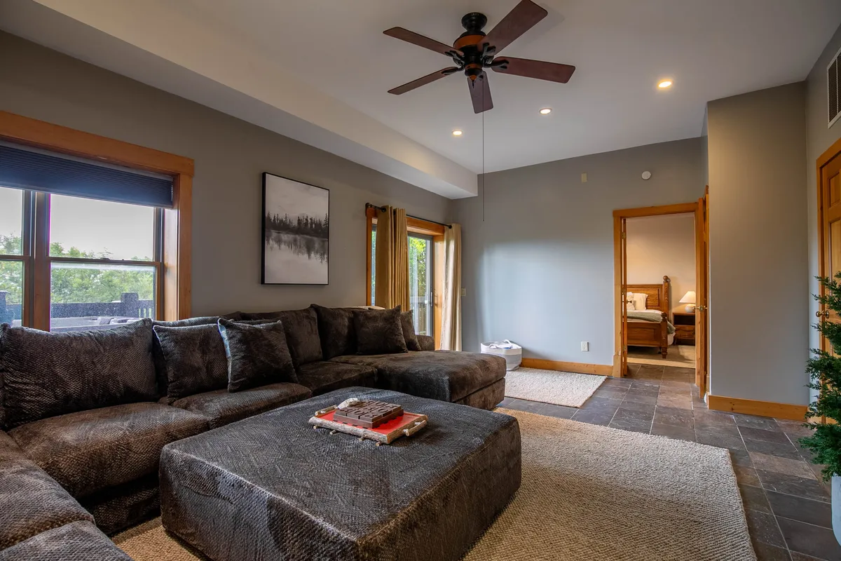 A spacious living area with a large sectional sofa, coffee table adorned with decor, and a window that fills the space with natural light. The setting is both comfortable and welcoming—perfect for relaxing after a day of exploration.