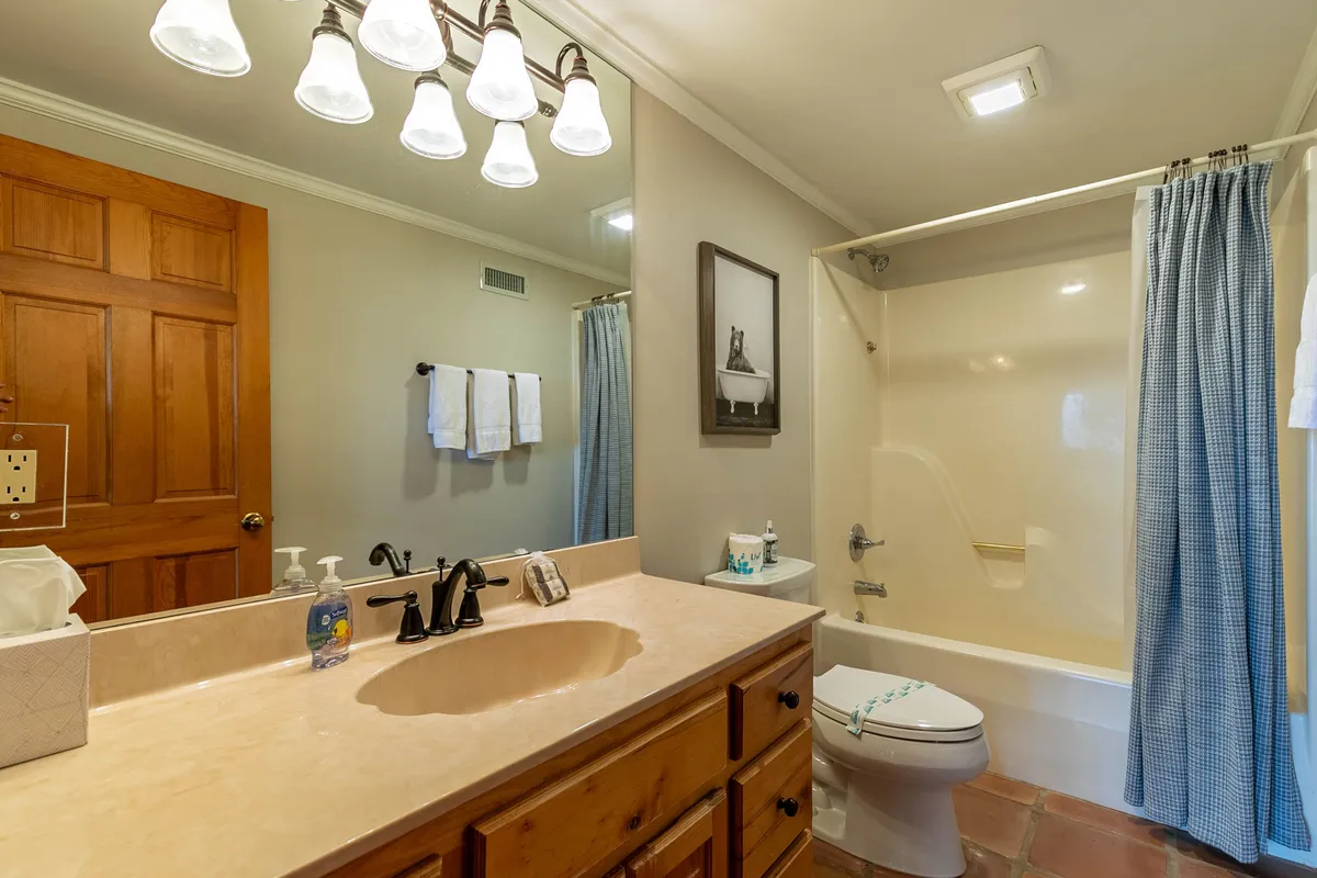 This image highlights a serene shared bathroom with a well-lit vanity, bathtub, and tasteful artwork. The calm, spa-like atmosphere is perfect for relaxation after a day of adventure.